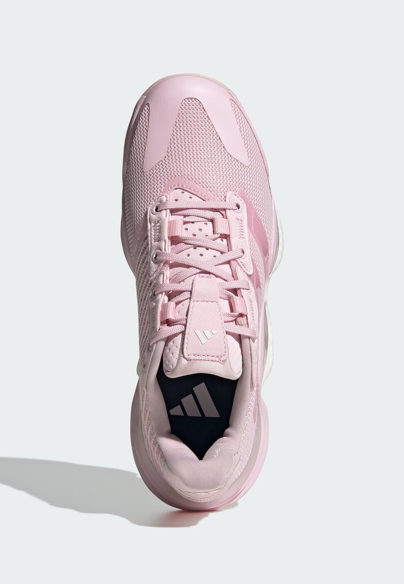 Zapatilla deportiva rosa con parte superior de malla, cierre de cordones y puntera reforzada, que presenta una superficie texturizada y un logo de tres franjas en la plantilla.