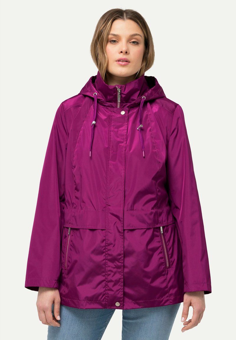 Lila vattentät jacka med huva, dragkedja fram och två sidofickor. Har justerbara dragsnören och en slät, glänsande yta.