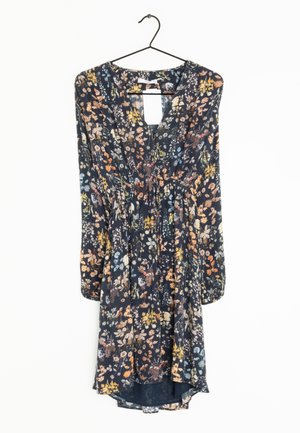 Langærmet, mørk blomsterkjole med indsnævret talje og v-hals, hængende på en sort trådbøjle mod en hvid baggrund.