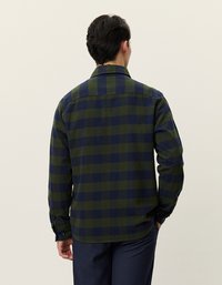 Zielona i granatowa flanelowa koszula w kratę z kołnierzykiem, długimi rękawami i mankietami zapinanymi na guziki. Posiada prosty dół i klasyczny wzór w kratę.