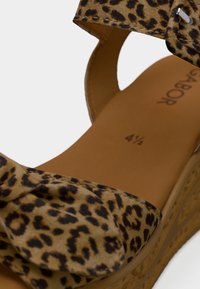 Σανδάλι πλατφόρμα με τύπωμα λεοπάρδαλης και λεπτομέρεια φιόγκου, κατασκευασμένο από υφασμάτινο υλικό με υφή. Διαθέτει καφέ εσωτερική σόλα με σημάνσεις μεγέθους και βάση με υφή τύπου φελλού.