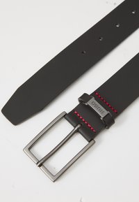 Ceinture en cuir noir avec une boucle carrée en argent, des coutures rouges et cinq trous pour l'ajustement. Design plat, texture lisse, forme rectangulaire.