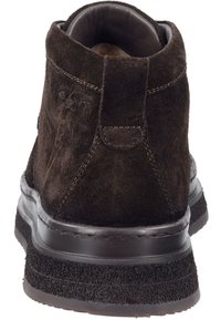 Bruine suède enkellaars met een ronde neus, gevoerde binnenkant en een gestructureerde rubberen zool. Subtiele stiksels en logo-detail aan de zijkant.