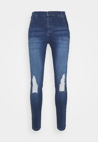 Vaqueros de denim azul ajustados con parches desgastados en las rodillas, que presentan una cintura alta y un diseño estándar de cinco bolsillos. Textura suave.
