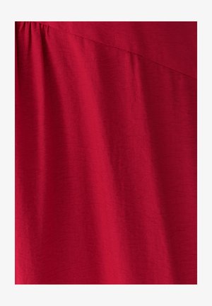 Punane kangas pehme, veidi tekstuurse pinnaga. Omab drapeeritud disaini, millel on ülaosas diagonaalne õmblus.