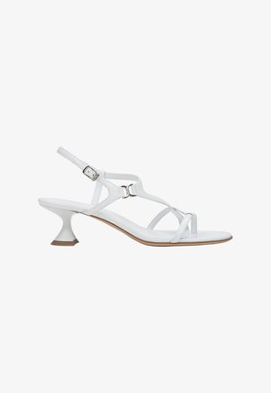 Bijele sandale sa zakrivljenom petom, s tankim remenčićima i kopčom za zatvaranje. Potplat je ravan i gladak s minimalnim detaljima.