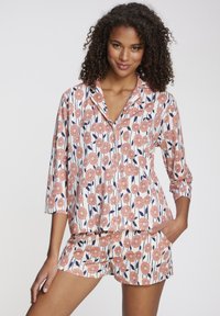 Floral-patterned pajama set in coral and navy on a white background; features a collared top and shorts with short sleeves.