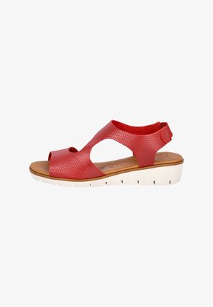 Sandalia de cuero rojo con un diseño texturizado, similar a reptil. Presenta puntera abierta, recortes y una suela blanca en estilo cuña con estrías.