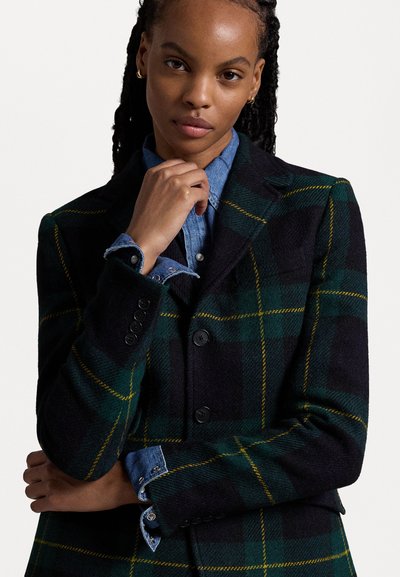 Blazer in plaid di lana nei colori verde scuro, nero e giallo. Presenta due bottoni, design strutturato e polsini in denim. Tessuto liscio con una vestibilità su misura.