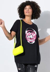 Camiseta negra con un diseño gráfico de calavera contorneado en rosa. Acompañada de un pequeño bolso cruzado texturizado en neón amarillo.