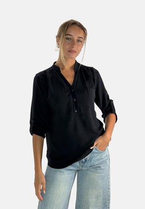 Zwarte blouse met kraag, knopenlijst en oprolbare mouwen. Zacht materiaal, ontspannen pasvorm, met een klein borstzakje.
