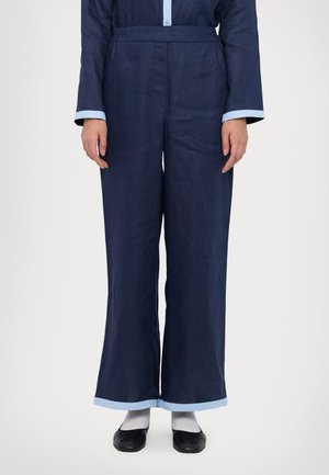 Pantaloni ample din in de culoare albastru închis, cu accente la tiv de culoare albastru deschis și o talie confortabilă. Au un croi lejer și un design minimalist.