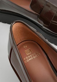 Mocassins en cuir marron avec semelles en caoutchouc noires, présentant des semelles intérieures rembourrées étiquetées "Forever Comfort" et une pointure 6½/40.