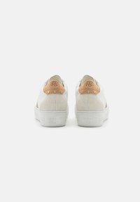 Sneakers bianchi con accenti in suede grigio e targhette in pelle marrone chiaro sul tallone. Presentano una superficie testurizzata, lacci piatti e una suola spessa di colore bianco.