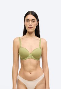Πράσινο επενδυμένο σουτιέν με κεντητό δαντέλα σε κυματιστό σχέδιο, ρυθμιζόμενους ιμάντες και ομαλή υφή. Ο σχεδιασμός έχει διακριτική γυαλάδα και κλείνει με αγκράφα.
