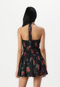 Musta kukkamekko smockattulla bodice-osa, halkio kaula-aukko ja lyhyt hame. Sisältää punaisia ruusuja ja vihreitä lehtiä tummalla taustalla.