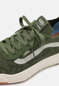 Groene mesh sneaker met witte zijstreep, textielstof, platte veters en een gevoerde zool; heeft het Vans-logo op de tong en het zijpaneel.