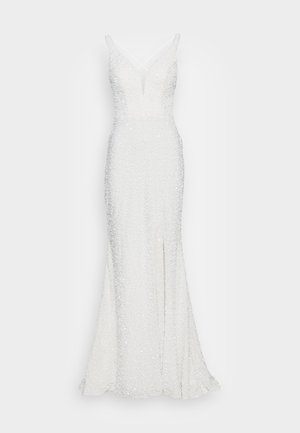 Hvit paljettlangkjole med en tettsittende silhuett, v-hals og tynne stropper. Har en sideslitt og texturert overflate.