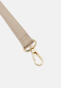 Sangle en cuir beige avec clip en métal doré, présentant des bords cousus et une texture lisse. Adaptée à divers accessoires.