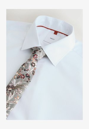 Weiß gestreiftes Hemd mit einem blumigen Krawatte in Grau, Pink und Rot, mit einem Etikett mit "NEXT" auf der Innenseite des Kragens.