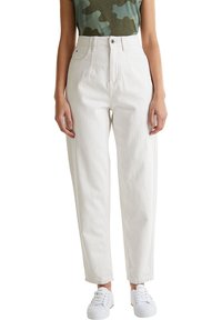 Jeans blancos de talle alto con un corte relajado, diseño de 5 bolsillos y cierre de botón. Combinados con una camiseta de patrón de camuflaje verde y zapatillas blancas.