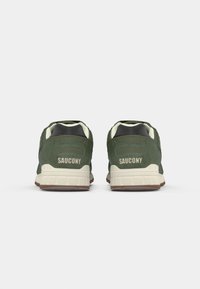 Zelene sportske tenisice od antilopa s debelim bijelim međuslojem i smešnim gumiranim potplatom. Imaju istaknuto "Saucony" brendiranje na peti.