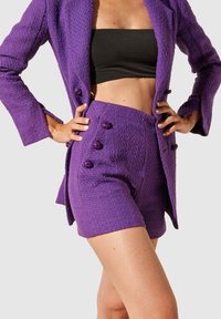 Veste texturée violette et short assorti avec des boutons décoratifs. L'ensemble présente une coupe ajustée et un tissu lisse.