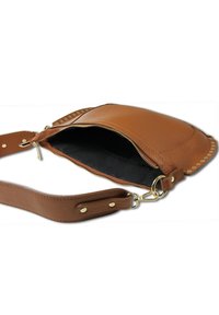 Sac bandoulière en cuir marron avec une forme courbée, fermeture zippée et accents cloutés. Il dispose d'un intérieur noir et d'une sangle réglable.