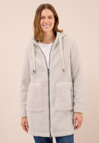 Manteau en polaire gris clair, doux et pelucheux, avec une fermeture éclair à l'avant, une capuche et des poches avant. Caractéristiques avec cordons de serrage et une finition douce et texturée.