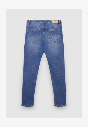 Jean denim bleu à coupe droite, design à cinq poches, léger délavage. Comprend une étiquette sur la ceinture et des détails cousus.