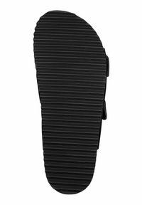 Semelle de sandale noire avec une texture nervurée et un bord lisse. Présente un design plat pour une meilleure adhérence, avec des sangles ajustables sur la partie supérieure.