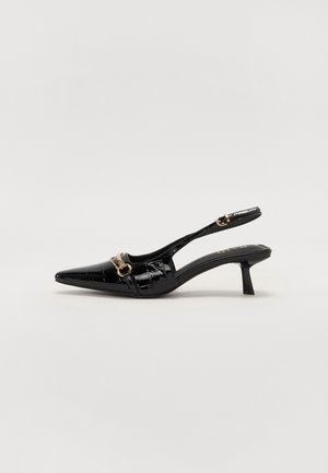 Czarne lakierowane sandały na niskim obcasie typu kitten heel z szpiczastym noskiem i złotą klamrą na przednim pasku, na białym tle.