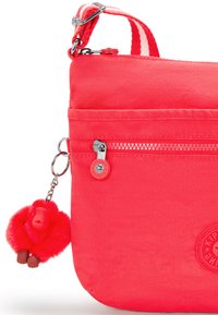 Rød crossbody taske med frontlynlås og tilhørende fluffy rød abe nøglekæde charm.