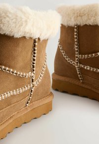 Bruna mocka ankellångstövlar med en mjuk krämfärgad fuskpälskrage, dekorativ vit sömnad och texturerade gummisålar.