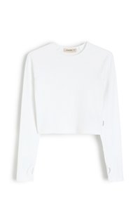 Biała krótka koszula z długim rękawem, okrągłym dekoltem, prążkowaną teksturą i rękawami raglanowymi. Posiada wycięcie na mankietach rękawów.