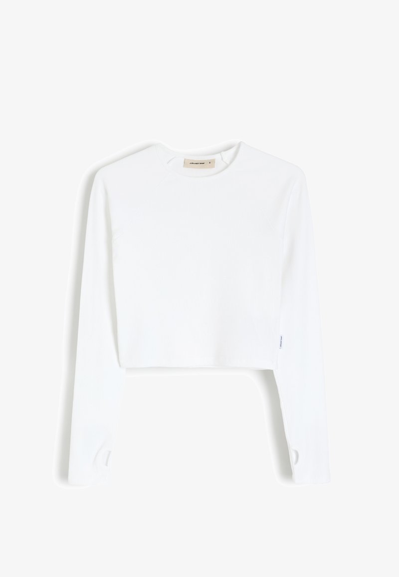 Biała krótka koszula z długim rękawem, okrągłym dekoltem, prążkowaną teksturą i rękawami raglanowymi. Posiada wycięcie na mankietach rękawów.