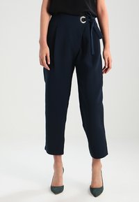 Granatowe spodnie o wysokim stanie o gładkiej fakturze, z szerokimi pętlami na pasek i przewiązanym paskiem z materiału. Otwarty dół i prosty krój.