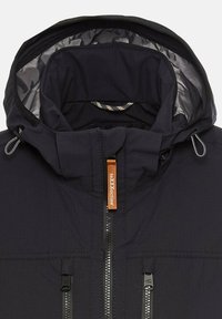 Donkerblauwe jas met een capuchon en een zilveren voering, contrasterende oranje ritssluiting en dubbele voorzakken met rits.