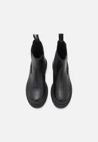 Czarne skórzane botki za kostkę z okrągłym noskiem, elastycznymi panelami bocznymi i uchwytem z tyłu. Teksturowana gumowa podeszwa, gładkie wykończenie cholewy.