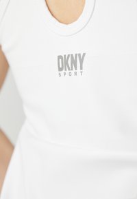 Λευκό αθλητικό τοπ με στρογγυλή λαιμόκοψη και το λογότυπο DKNY SPORT εκτυπωμένο σε γκρι. Απαλή υφή υφάσματος με εφαρμοστή σχεδίαση.