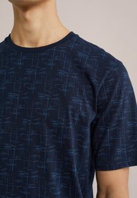 Tengerész navy crew neck póló, puha pamutból készült, világos kék geometrikus mintával, rövid ujjal és normál fazonnal.