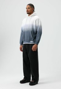 Grijze ombre hoodie met een kangaroezak en capuchon met trekkoord, gecombineerd met zwarte wijde broekspijpen en zwarte schoenen. Gladde textuur, relaxte pasvorm.