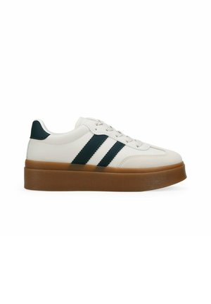 Zapatilla blanca con rayas verdes, suela de goma y un diseño elegante. Presenta un acabado texturizado y cordones planos.