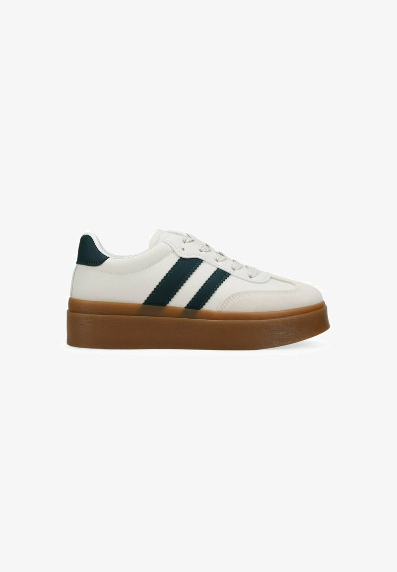 Zapatilla blanca con rayas verdes, suela de goma y un diseño elegante. Presenta un acabado texturizado y cordones planos.