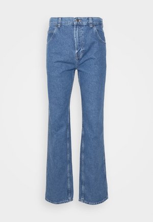 Jeans flare em denim azul com uma cintura alta, apresentando passantes para cinto, bolsos frontais e um fecho clássico com botão. Textura suave, costuras retas.