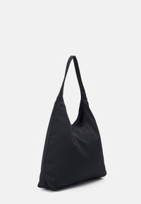 Černá ramenní taška z měkké tkaniny s unikátním trojúhelníkovým tvarem, širokým uchem a minimalistickým designem bez viditelného kovového spojení.