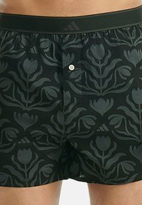 Černé boxerky s květinovým vzorem, zapínání na knoflík a elastický pás se znakem Adidas. Bavlněný materiál.