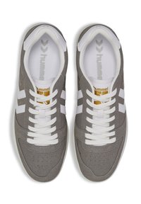 Gray suede sneakers with white accents, featuring a lace-up design, perforations on the toe, and a textured rubber sole. Brand logo on tongue.