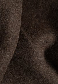 Bruin viltstof met een zachte textuur, die een rijke, donkere tint en subtiele variaties in kleur en diepte over het oppervlak vertoont.