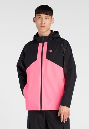 Veste à capuche légère, noire et rose vif avec un design géométrique, fermeture éclair à l'avant et logo New Balance sur la poitrine.